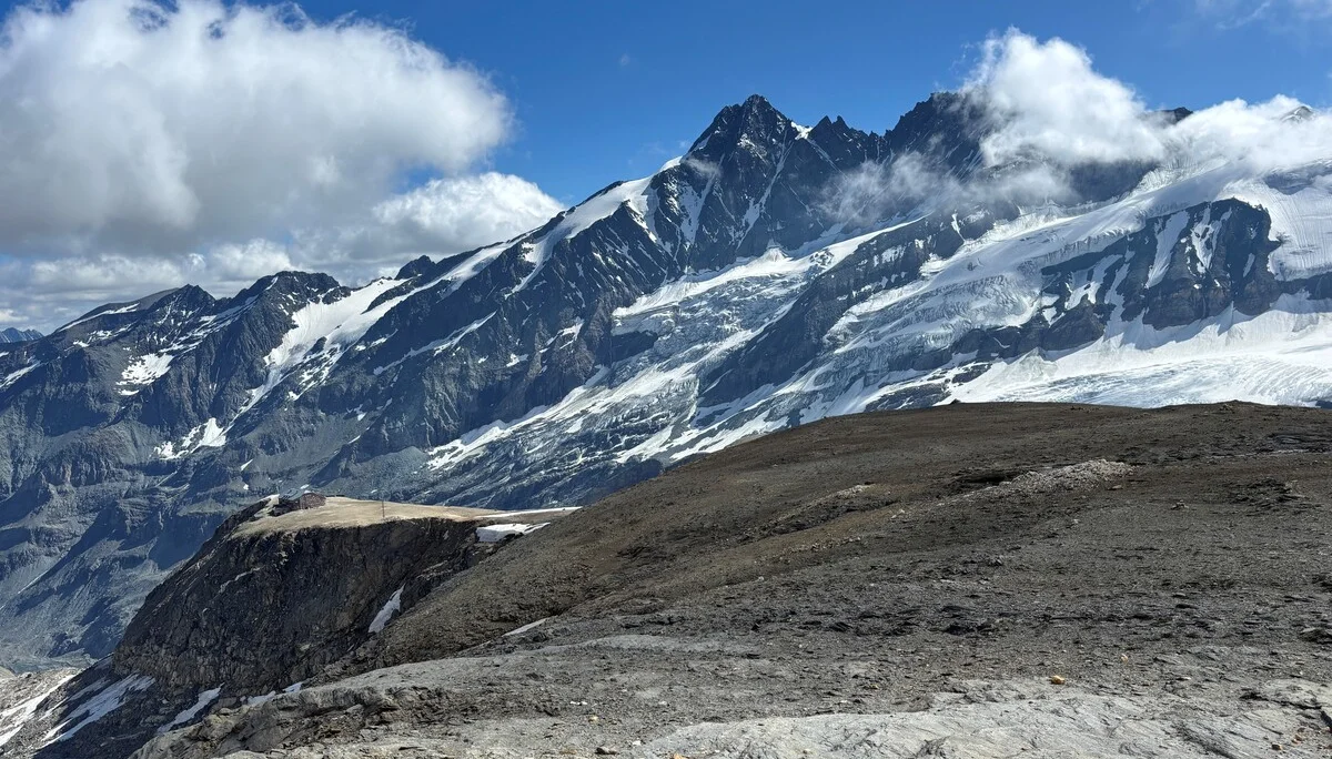 Schneebedeckte Berggipfel unter blauem Himmel mit Wolken, davor felsiges, vegetationsarmes Gelände | © Steffen Wolf