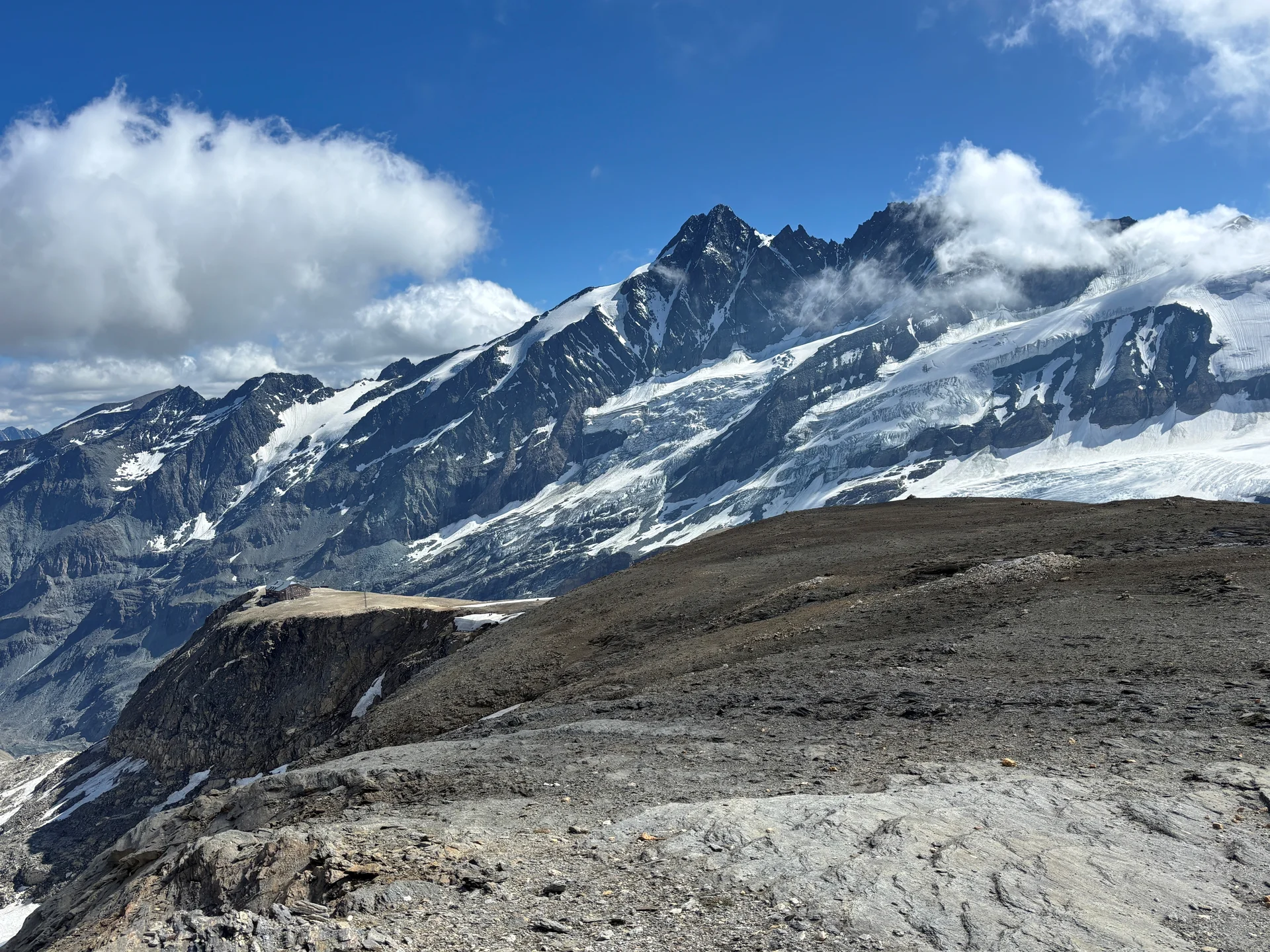 Schneebedeckte Berggipfel unter blauem Himmel mit Wolken, davor felsiges, vegetationsarmes Gelände | © Steffen Wolf