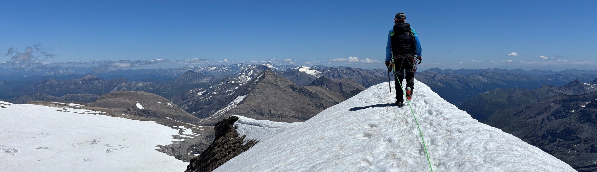 Bergsteiger mit Rucksack und Seil wandert auf schneebedecktem Grat unter klarem blauem Himmel | © Steffen Wolf