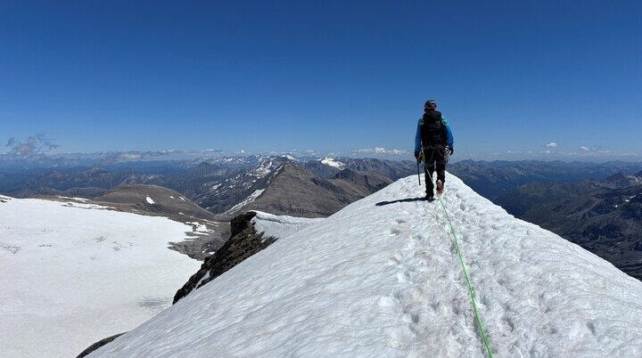 Bergsteiger mit Rucksack und Seil wandert auf schneebedecktem Grat unter klarem blauem Himmel | © Steffen Wolf