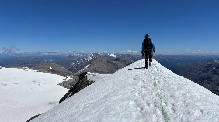 Bergsteiger mit Rucksack und Seil wandert auf schneebedecktem Grat unter klarem blauem Himmel | © Steffen Wolf