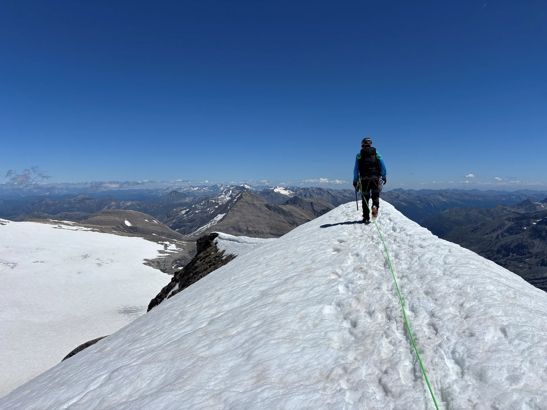Bergsteiger mit Rucksack und Seil wandert auf schneebedecktem Grat unter klarem blauem Himmel | © Steffen Wolf