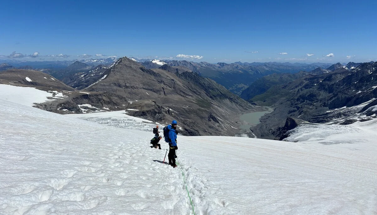 Zwei Bergsteiger mit blauer und schwarzer Kleidung steigen auf einem schneebedeckten Gletscher in den Alpen auf | © Steffen Wolf