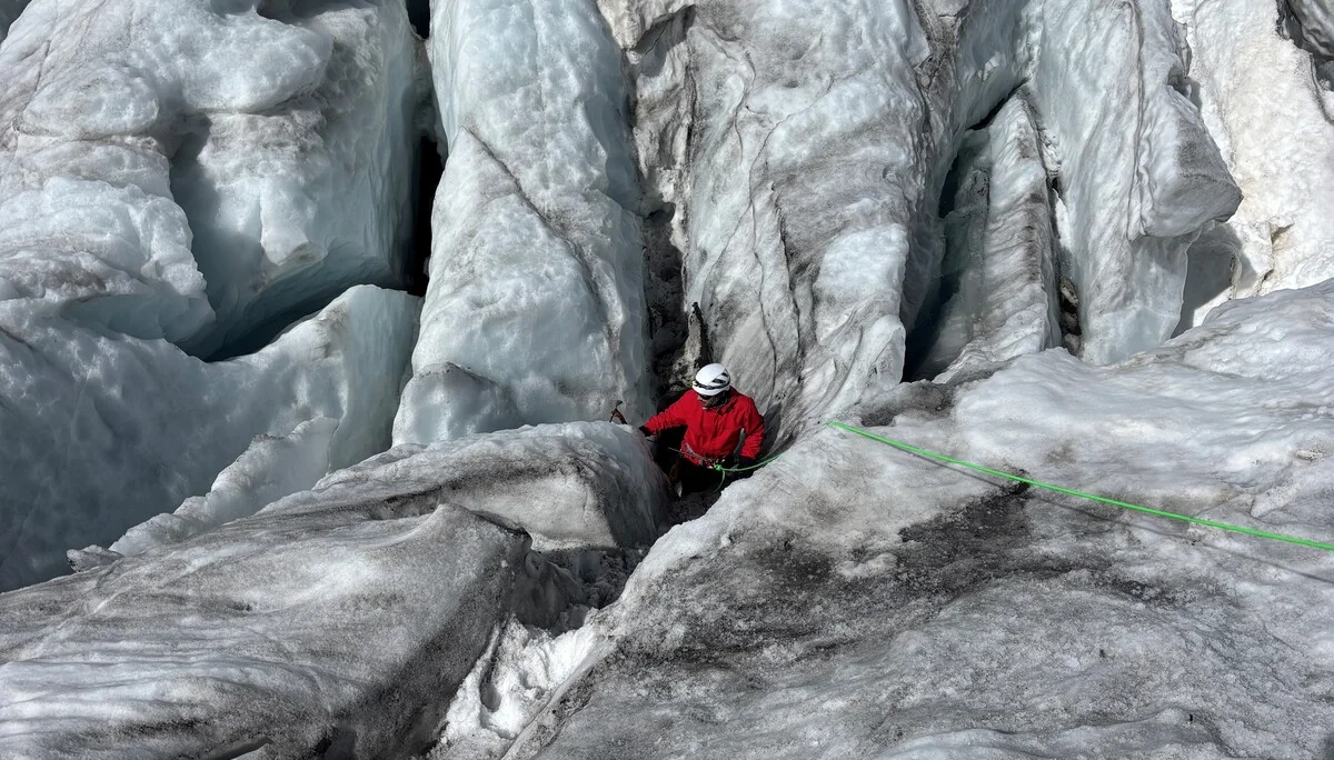Bergsteiger in roter Jacke klettert an einem Gletscher mit tiefen Spalten und Eisformationen | © Steffen Wolf