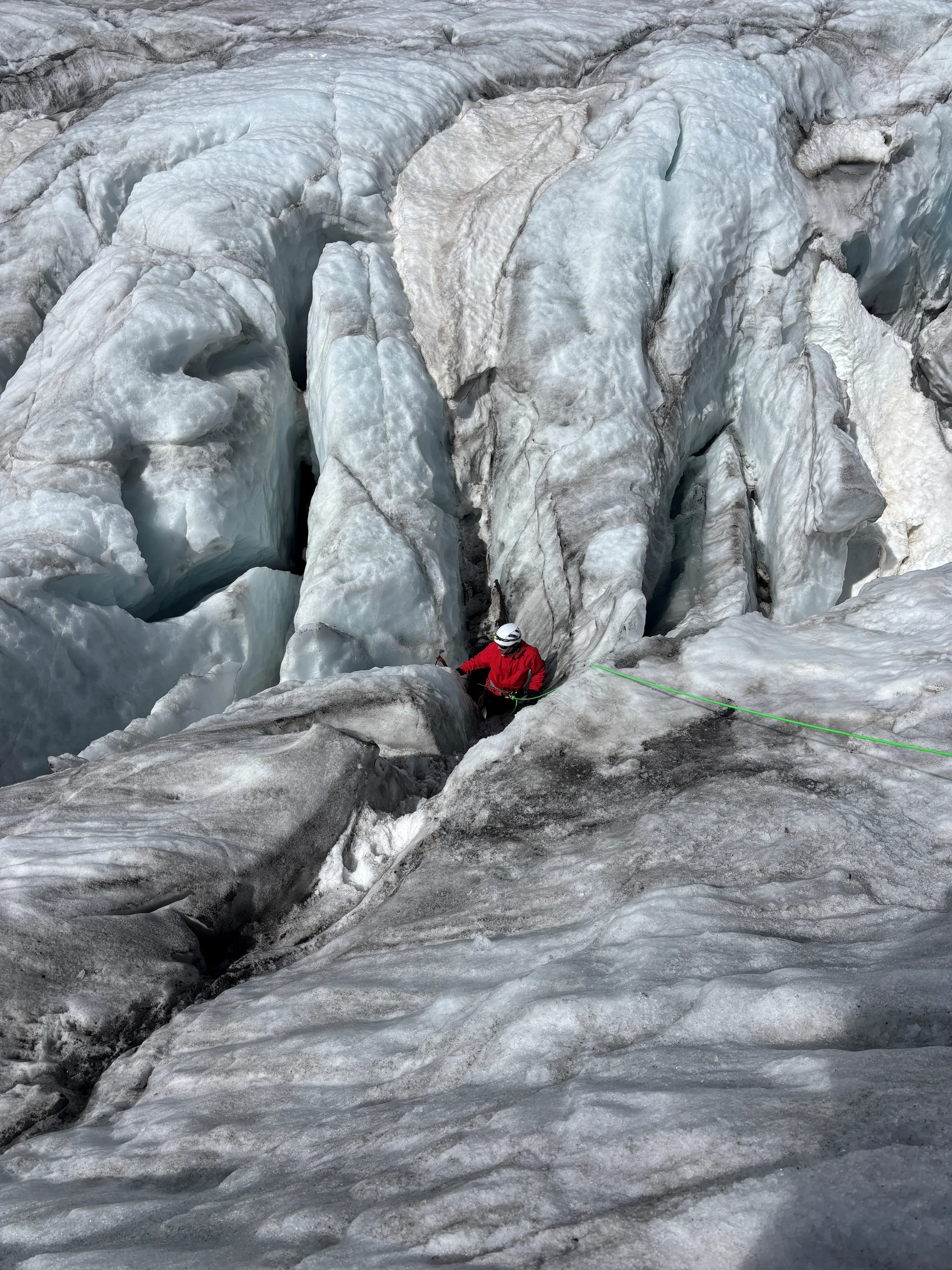 Bergsteiger in roter Jacke klettert an einem Gletscher mit tiefen Spalten und Eisformationen | © Steffen Wolf