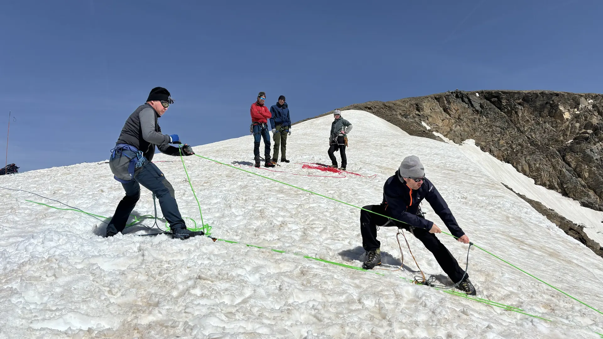 Zwei Personen sichern sich mit Seilen auf einem schneebedeckten Hang, zwei weitere Personen beobachten | © DAV Sektion Geltendorf