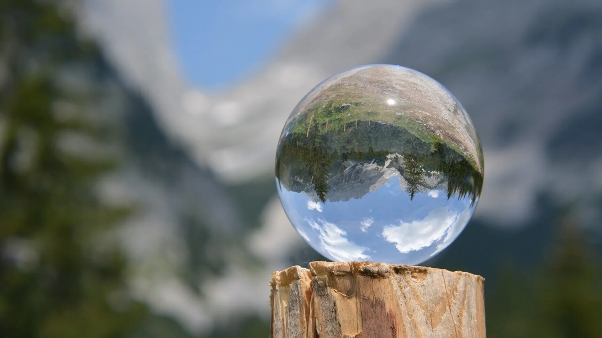 Glaskugel auf einem Holzpfosten zeigt spiegelverkehrte Berglandschaft mit blauem Himmel und Wolken | © DAV Sektion Geltendorf