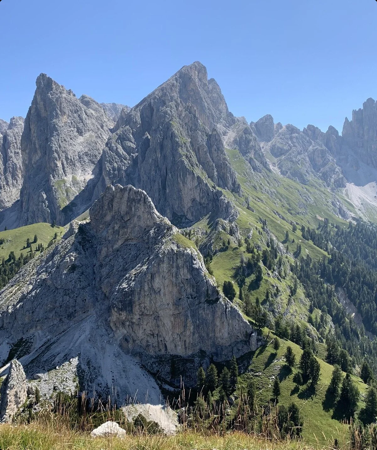 Berglandschaft mit schroffen Felsen und grünen Wiesen unter klarem blauem Himmel in den Dolomiten | © DAV Sektion Geltendorf