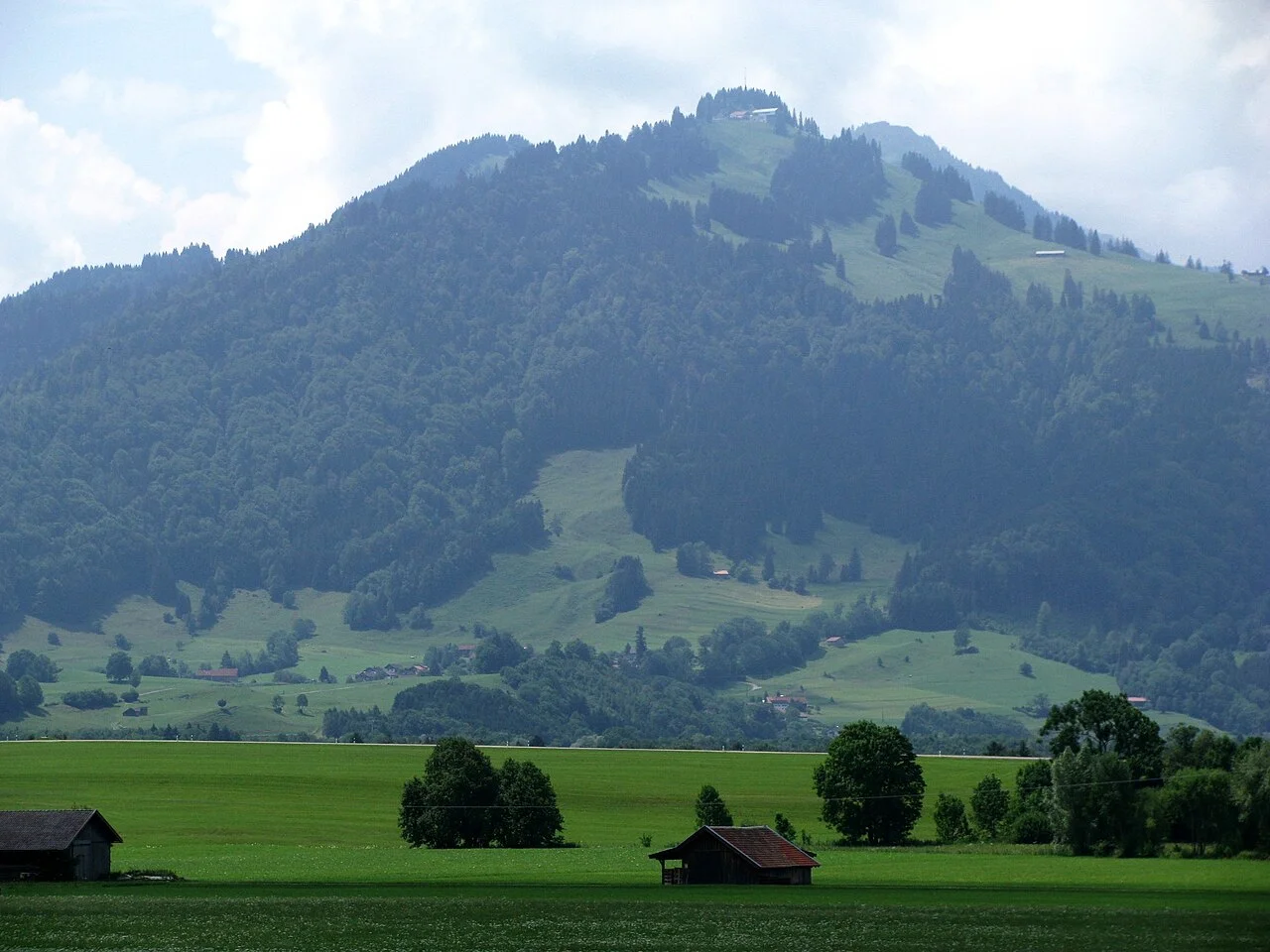 Berg Fockenstein mit bewaldeten Hängen und grünen Wiesen im Vordergrund, vereinzelt kleine Holzhäuser | © DAV Sektion Geltendorf