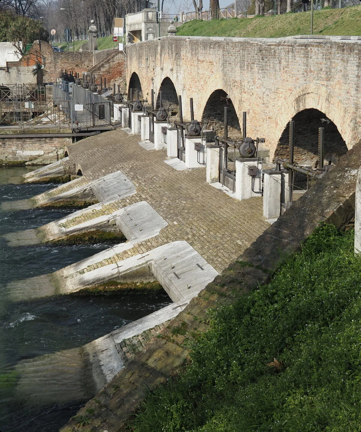 Historische Schleuse mit Backsteinbrücke in Italien. Fluss mit Wasserwehren und antiken Bauwerken. Sehenswürdigkeit und Tourismus in Italien. Flusslandschaft mit Schleusentor. | © Christoph Maier