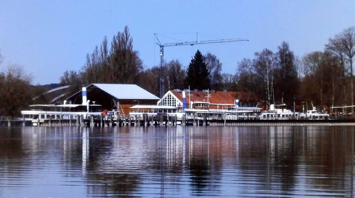 Hafen mit Stegen und Gebäuden am Ufer des Ammersees, ruhiges Wasser spiegelt die Szenerie | © Hartmut Engel